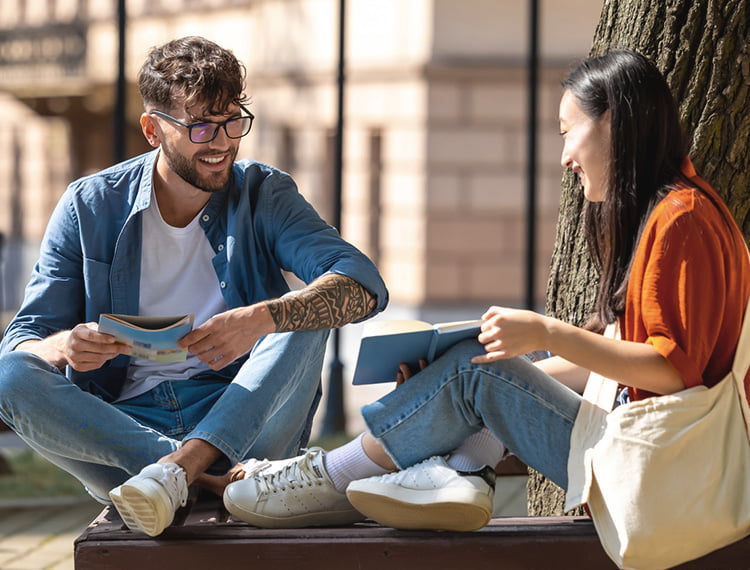 Two friends sitting near a tree