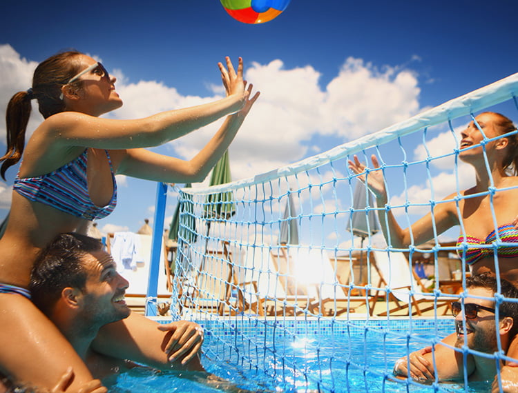 Friends playing volleyball in the pool